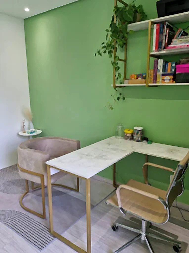 Sala de atendimento, com parede verde, poltrona e mesa